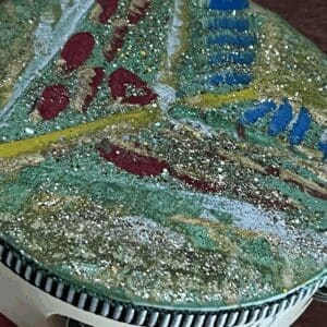Close-up of a colorful, textured painting with glitter and abstract shapes.