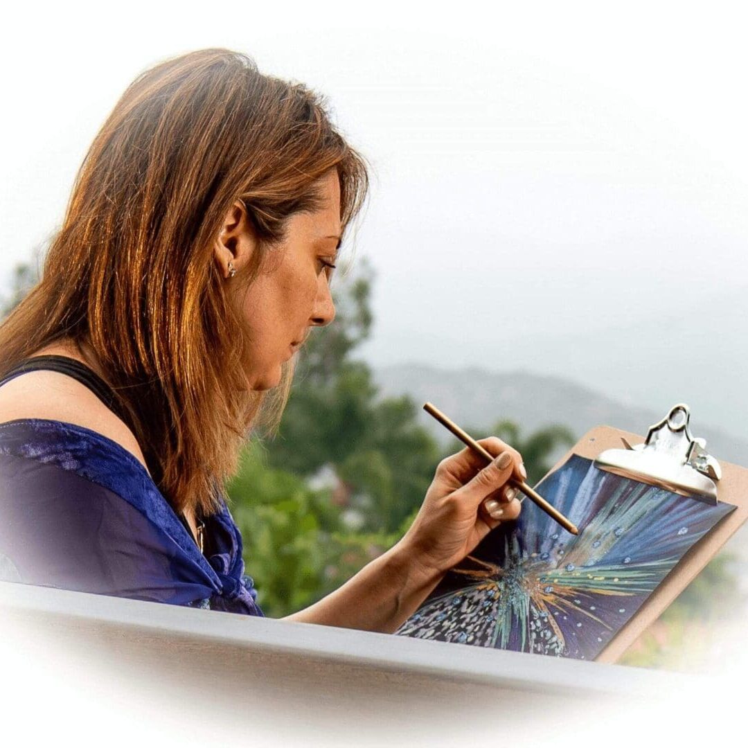 Side view of Lisa Nomikos painting outdoors with a brush on black paper.